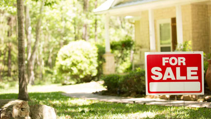 A 'for sale' sign sits in front of a house