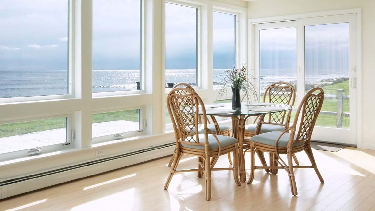 A dining room in a beach house with large windows 