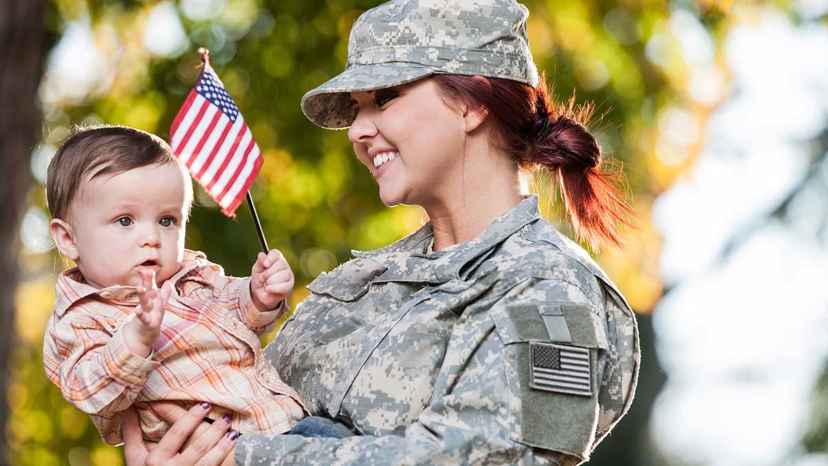veteran mom holding her baby waving an American flag
